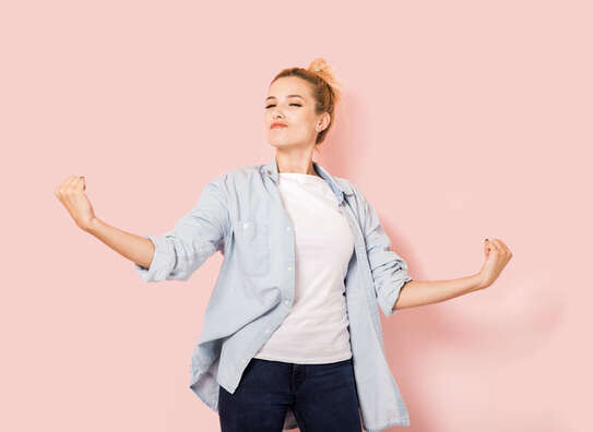 Selbstbewusste Frau steht vor rosa Hintergrund