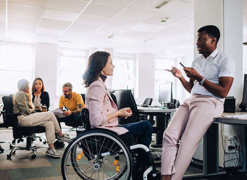 Frau im Rollstuhl unterhält sich mit Arbeitskollegen